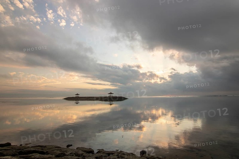 Beautiful seascape in the morning. Tropical sandy beach with breakwater and reflection of the sky in the calm water. Morning landscape, taken in Sanur, Bali, Indonesia, Asia