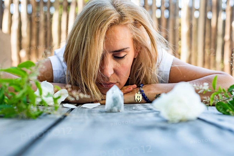 Portrait of a woman lying on the floor with her eyes closed. White crystals and roses around