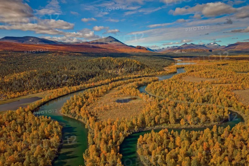 Drone shot, view of the Änok marshland with river Kamajakka, birch forests, autumn, intense colours, Vallespiken mountain on the left, Sarek mountains in the background, Kvikkjokk, Jokkmokk, Norrbottens län, Lapland, Northern Sweden, Sweden, Europe