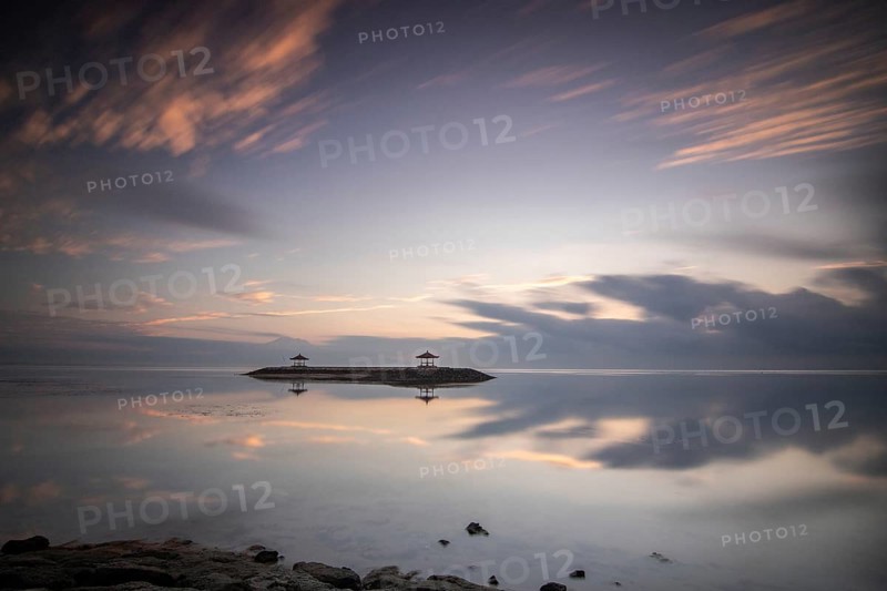 Beautiful seascape in the morning. Tropical sandy beach with breakwater and reflection of the sky in the calm water. Morning landscape, taken in Sanur, Bali, Indonesia, Asia