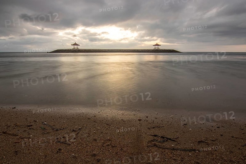 Beautiful seascape in the morning. Tropical sandy beach with breakwater and reflection of the sky in the calm water. Morning landscape, taken in Sanur, Bali, Indonesia, Asia