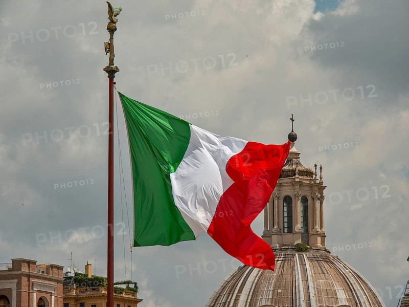 The Italian flag flies dynamically in front of a dome under a cloudy sky, rome, italy