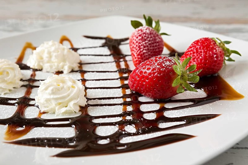 Strawberries and whipped cream with decorations over a square plate