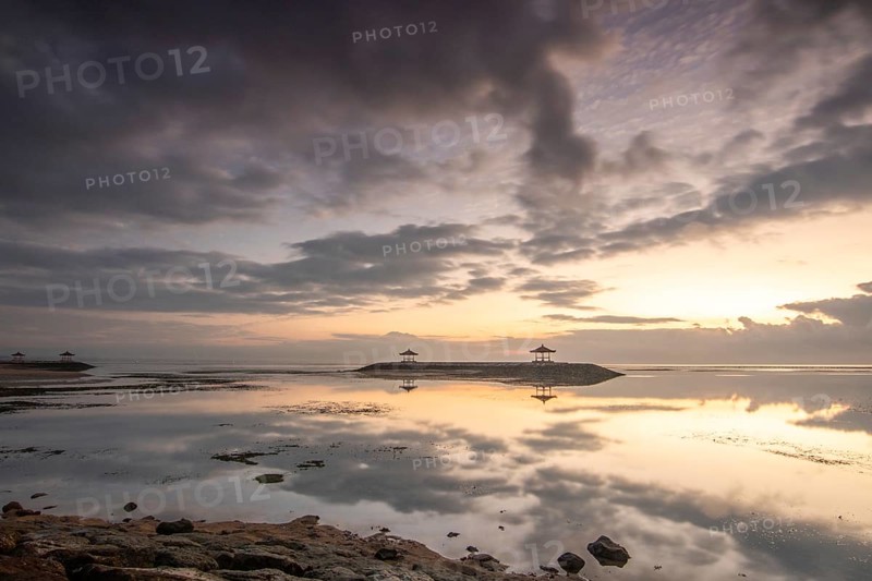 Beautiful seascape in the morning. Tropical sandy beach with breakwater and reflection of the sky in the calm water. Morning landscape, taken in Sanur, Bali, Indonesia, Asia