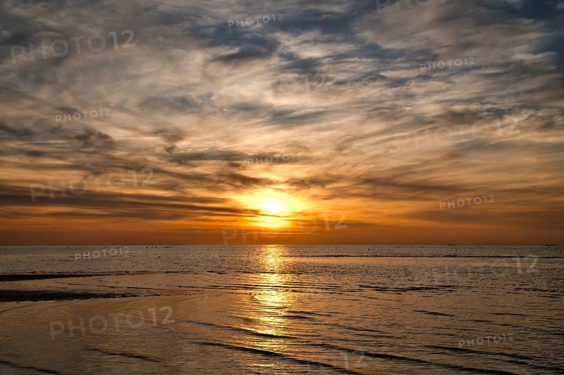 Sunset, illuminated sea. Sandy beach in the foreground. Light waves. Poel island on the Baltic Sea. Nature photo from the coast