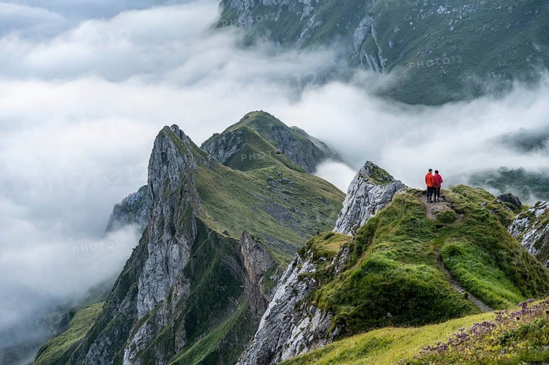 Two hikers enjoying the view over the Säntis mountains into the valley of Meglisalp at sunrise, high fog in the valley, Säntis, Appenzell Ausserrhoden, Appenzell Alps, Switzerland, Europe