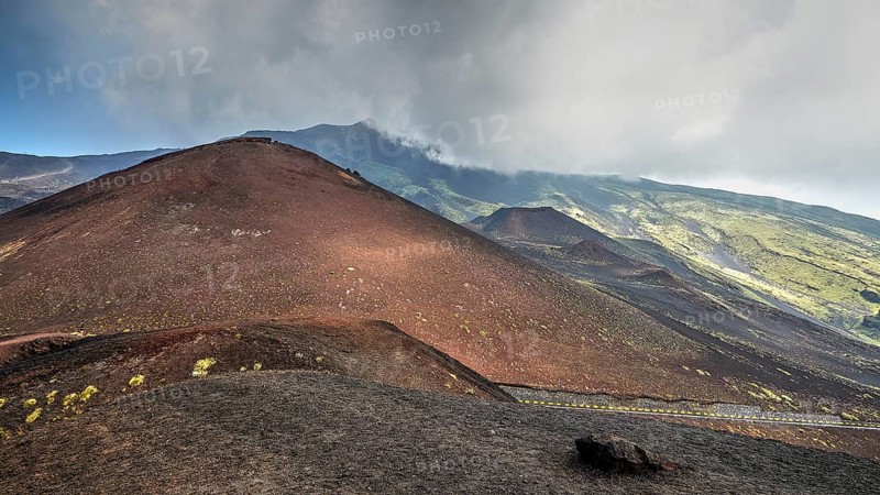 Red lava hill, cloudy sky, black crater, green mountain slopes, Crateri Silvestri, Etna, volcano, Eastern Sicily, Sicily, Italy, Europe