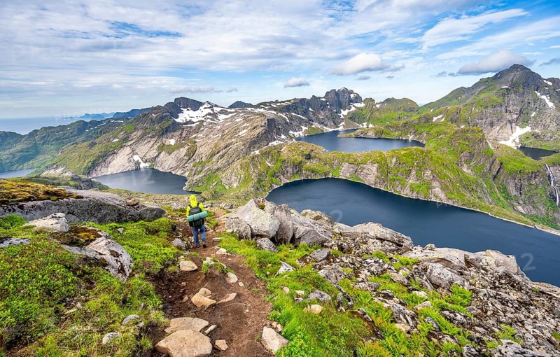 Mountaineers on a hiking trail, mountain landscape with steep rocky mountain peaks and lake Tennesvatnet, Krokvatnet and Fjerddalsvatnet, in the back peak of Hermannsdalstinden, view from the top of Munken, Moskenesoya, Lofoten, Nordland, Norway, Europe