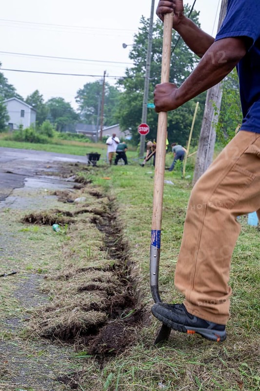 Detroit, Michigan, Volunteers clear weeds and grass in preparation for planting a roadside garden in the Morningside neighborhood