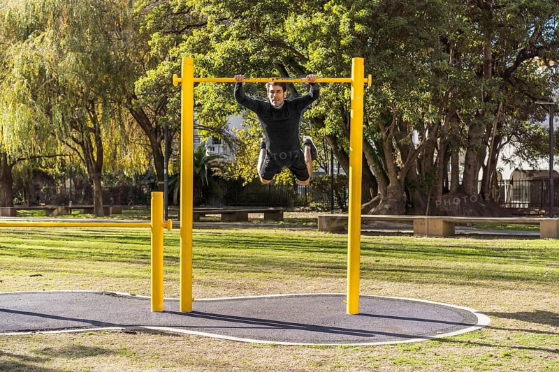 Attractive athlete doing exercises on a crossbar in a public car