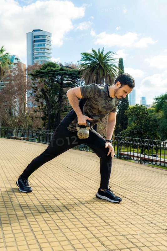Young latin man doing exercises with kettlebell outdoor. Weightlifting workout. Sports, fitness concept