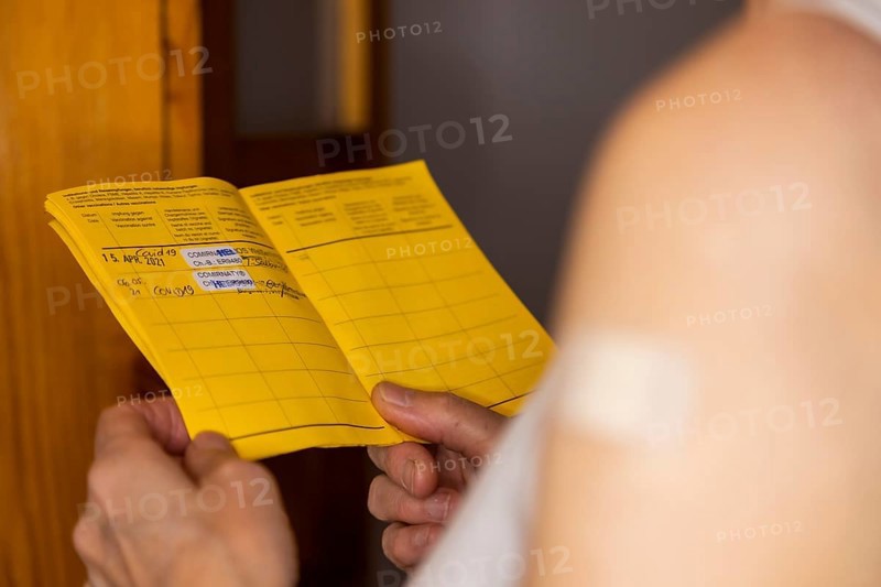 Woman vaccinated with a corona agent looks at her vaccination card