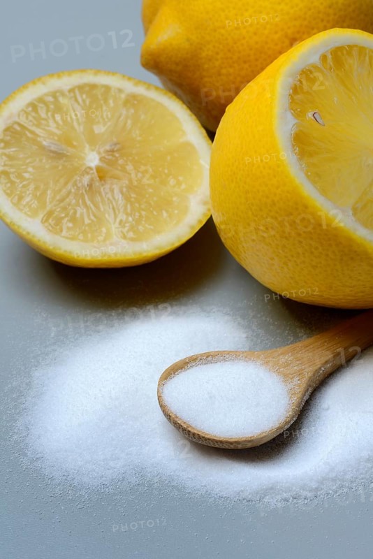 Citric acid in wooden spoon and lemon