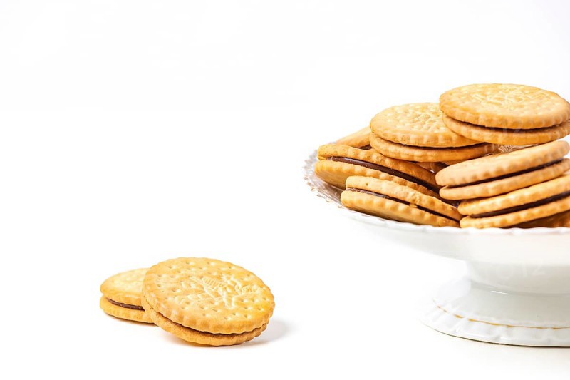Double biscuits in and next to white bowl, white background, copy space