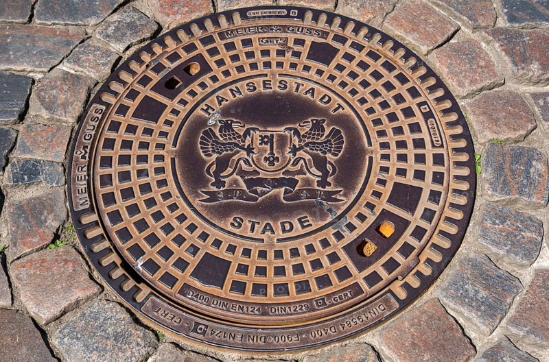 Manhole cover, manhole cover with city coat of arms and cobblestones, Hanseatic City of Stade, Lower Saxony, Germany, Europe