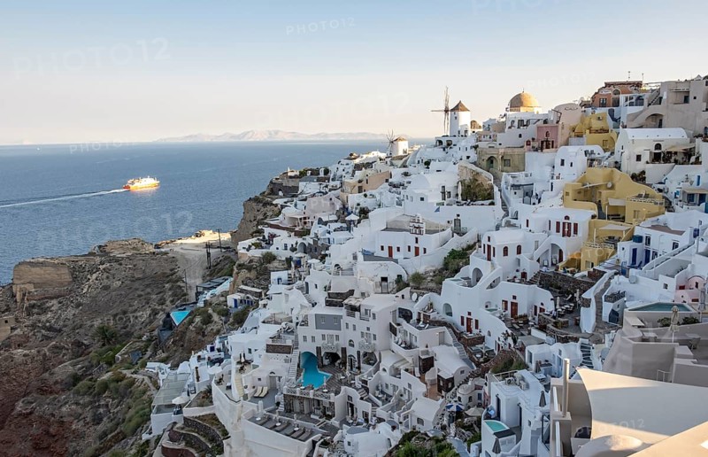 Cliff-side houses, villas and windmill in the village of Oia, Ia, as seen from the Kasteli Castle, Santorini, Greece, Europe