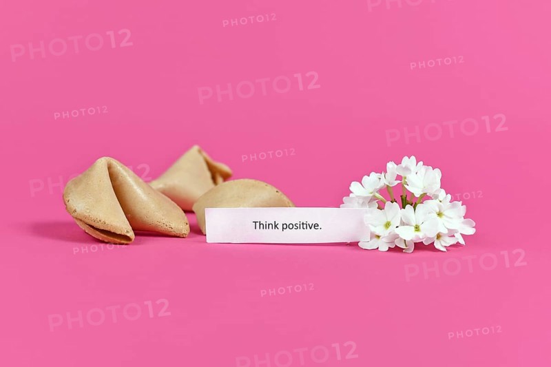 Positive thinking concept with fortune cookies with motivational text saying Think positive on pink background