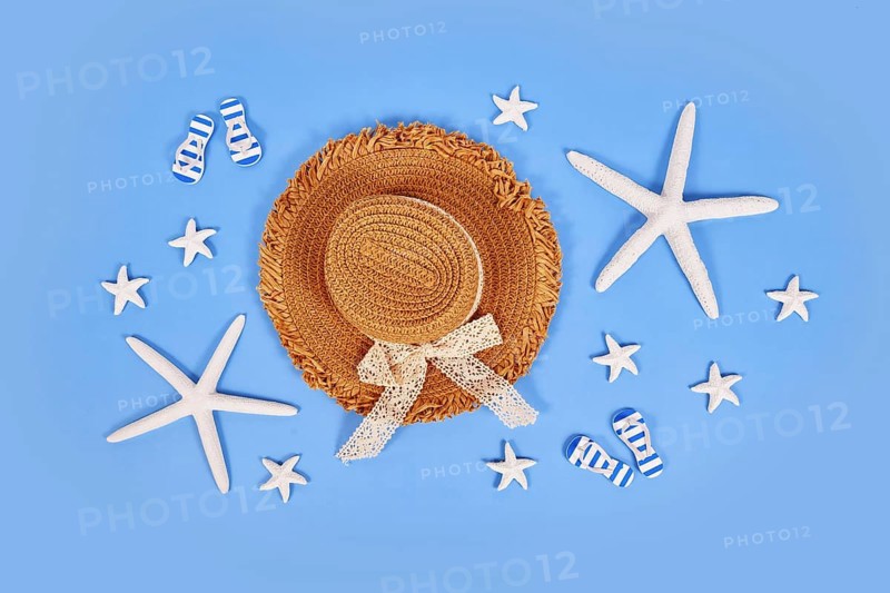 White starfish, summer straw hat and sandals on blue background