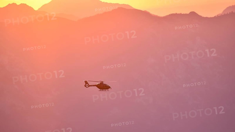 Rescue helicopter Christoph in flight in the evening over the Berchtesgaden Alps, Bavaria, Germany, Europe