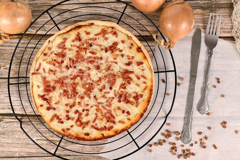 Taditional food 'Tarte Flambee' or 'Flammkuchen' from German-French Alsace border region. Name means pie baked in the flames, similar to a thin pizza with bacon and soured cream
