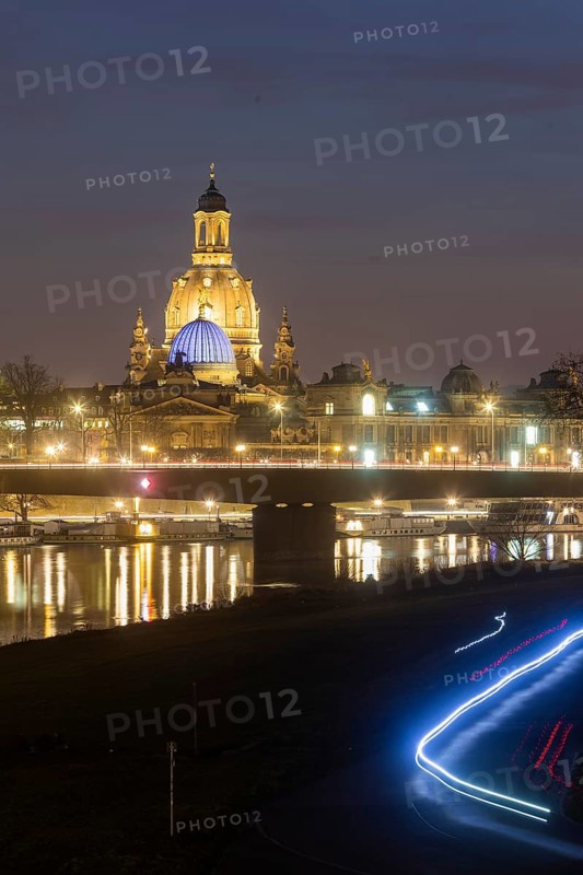 The Church of Our Lady with the glass dome above the octagon of the Academy of Arts, which is illuminated in blue in protest against the Ukraine war. In the foreground, light strips of cyclists in the dark on the Elbe cycle path