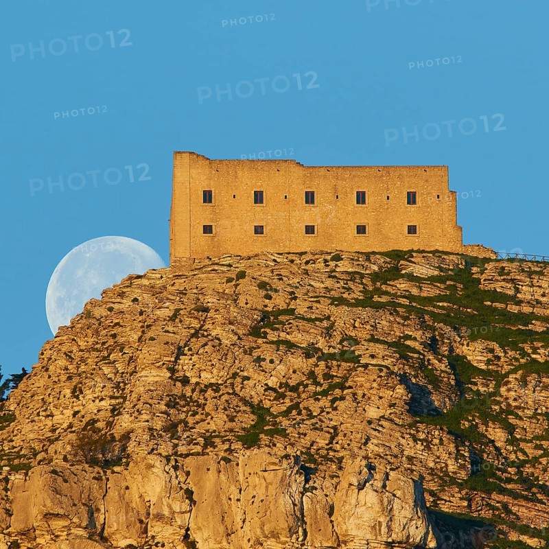 Morning light, super clear blue sky, huge full moon, sets behind mountain, fortress-like building on the mountain, super telephoto, Erice, Trapani province, mountain, Sicily, Italy, Europe