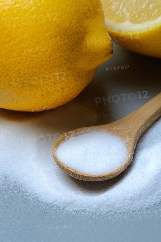 Citric acid in wooden spoon and lemon