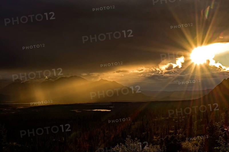 Sun in the evening breaks through the dense cloud cover in the subarctic tundra landscape, Denali Highway, Alaska, USA, North America