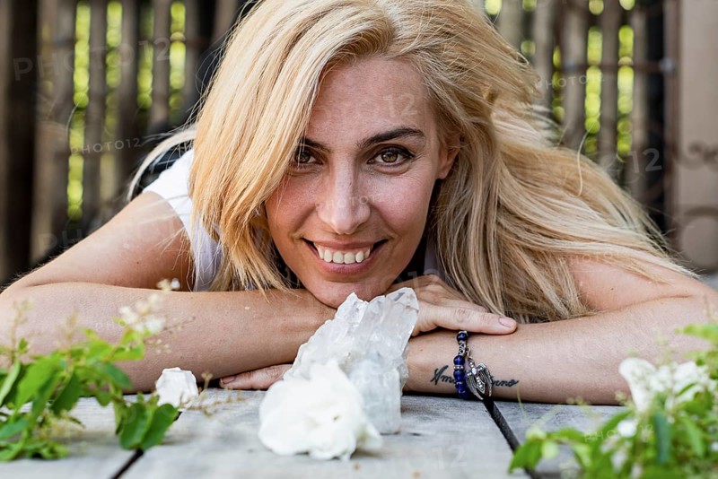 Portrait of a beautiful woman lying on the floor while looking at camera. White crystals and roses around