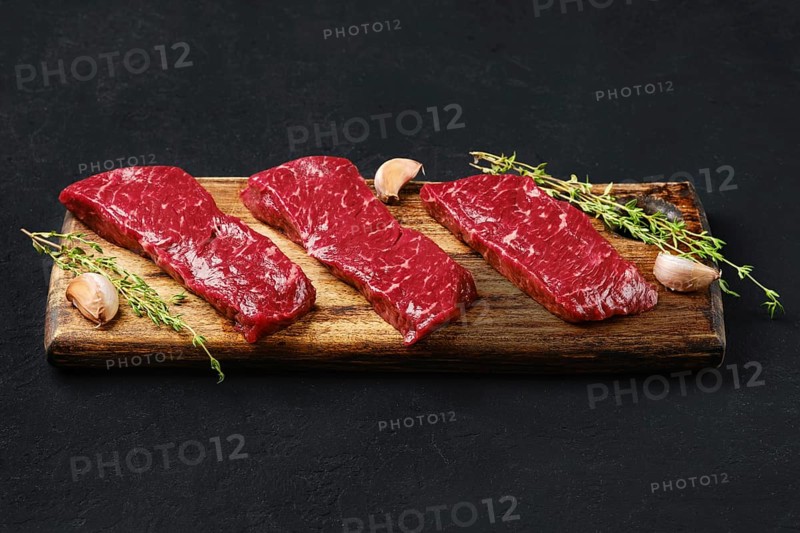 Raw strip steak boneless on wooden cutting board