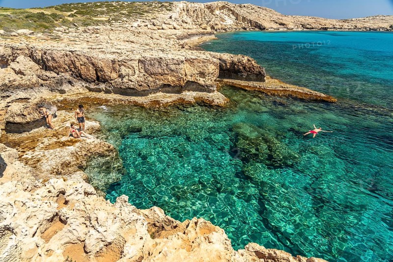 Tourists bathing in the crystal-clear turquoise waters of the Cape Greco peninsula, Agia Napa, Cyprus, Europe