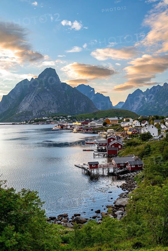 Village view of the fishing village Reine, traditional red Rorbuer cabins, at sunset, in the back rocky mountains with peak Olstinden, Lofoten, Nordland, Norway, Europe