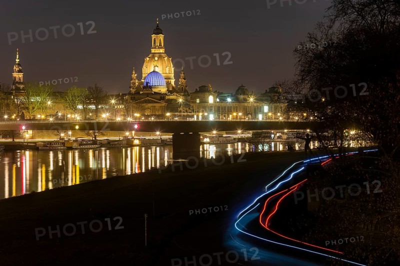 The Church of Our Lady with the glass dome above the octagon of the Academy of Arts, which is illuminated in blue in protest against the Ukraine war. In the foreground, light strips of cyclists in the dark on the Elbe cycle path
