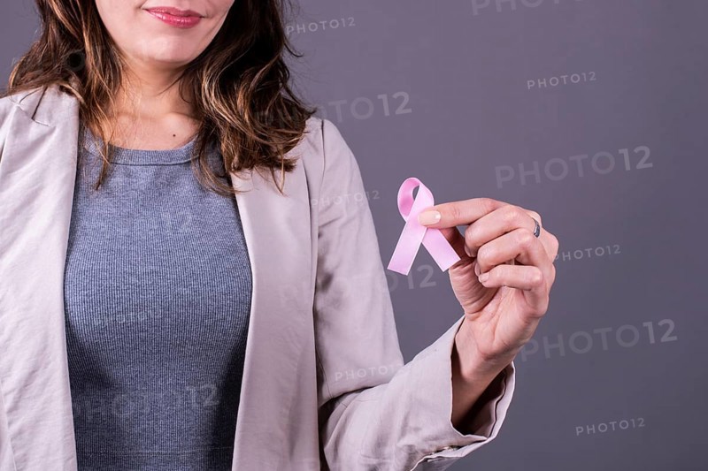 Close-up of a pink badge ribbon holded by a woman to support breast cancer cause