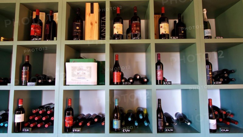 Shelves with a variety of wine bottles and price labels in a wine shop, Planeta winery, Sicilian wine, Sicily, Italy, Europe