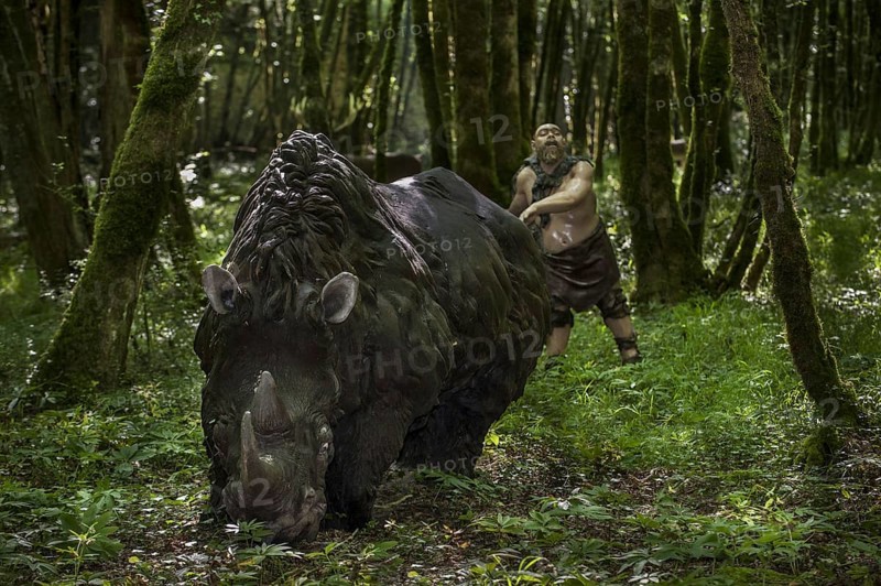Diorama showing Neanderthal hunter chasing woolly rhinoceros (Coelodonta antiquitatis) at Prehisto Parc, theme park about prehistoric life at Tursac, Périgord, Dordogne, France, Europe