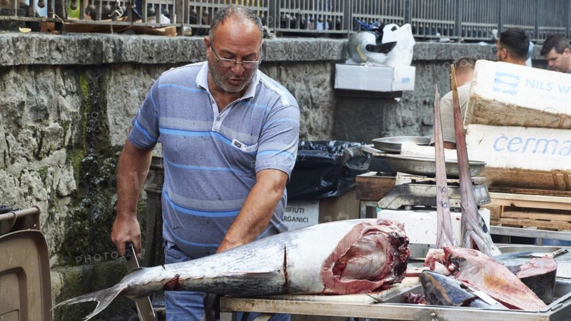 Vendor cuts up huge tuna with a cleaver, fish market, old town, Catania, east coast, Sicily, Italy, Europe
