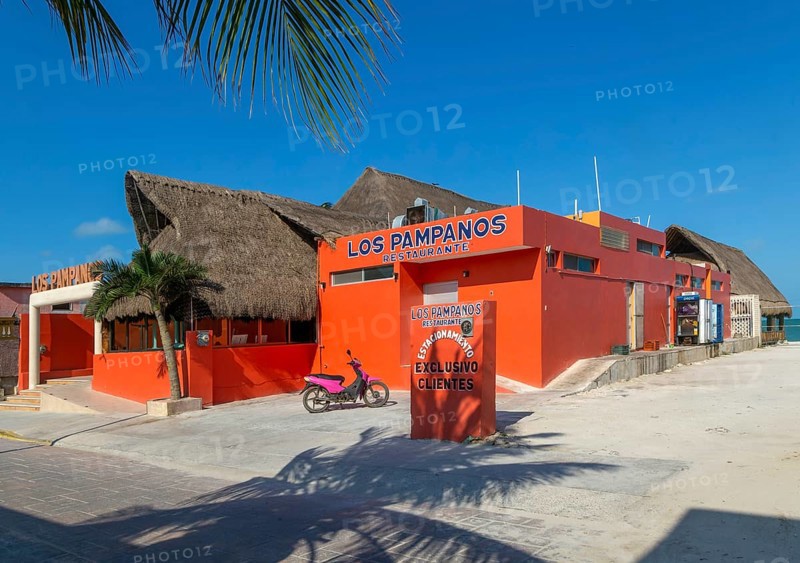 Thatched palapa roofed buildings and bright orange exterior of Los Pampanos seaside restaurant, Celestun, Yucatan, Mexico, Central America