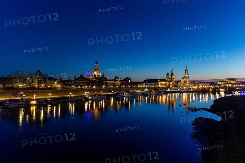 Skyline of Dresden's old town, illuminated in the evening. On the terrace bank on the Elbe, the dome of the Fama, the Church of Our Lady, the Secundo Genitur, the Ständehaus, the Hofkirche, the Schlossturm and the Semperoper are reflected in the river