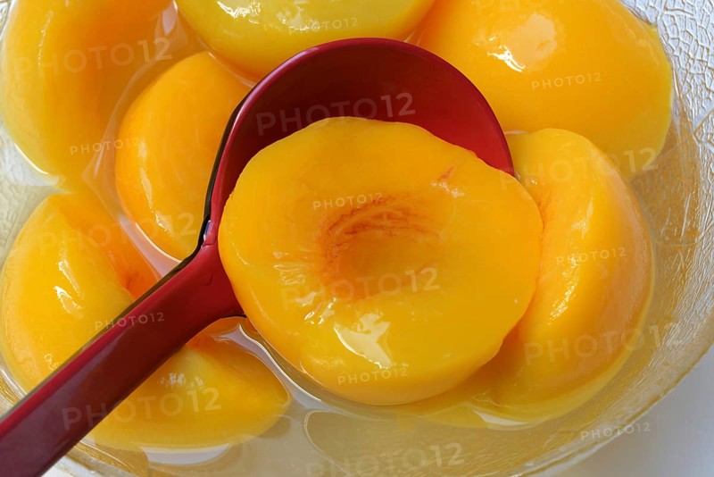 Peach, peach halves in syrup with ladle (Prunus persica)
