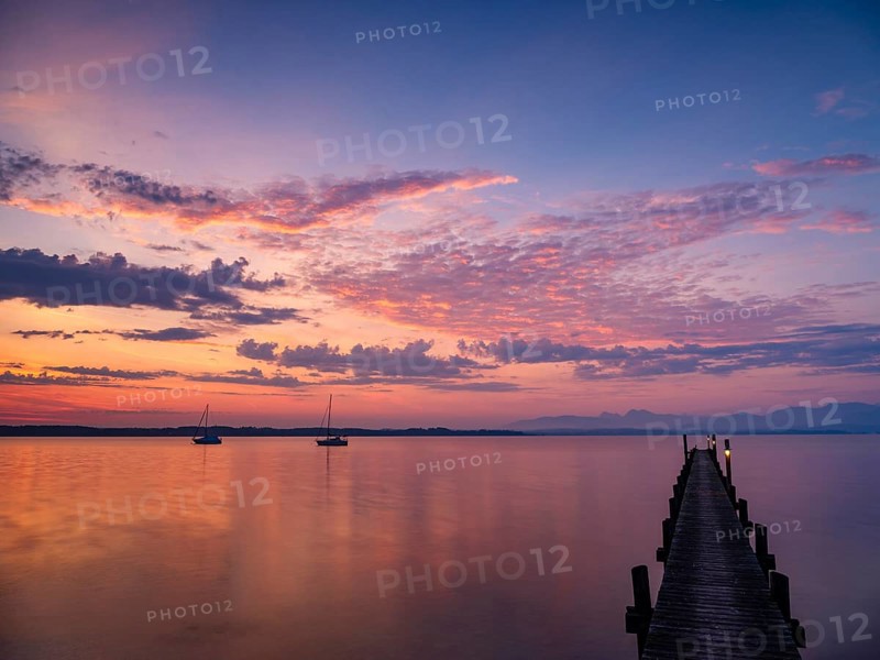 Illuminated clouds over sailing boats and jetty at Chiemsee at dawn, behind the Chiemgau Alps, Chiemgau, Upper Bavaria, Bavaria, Germany, Europe