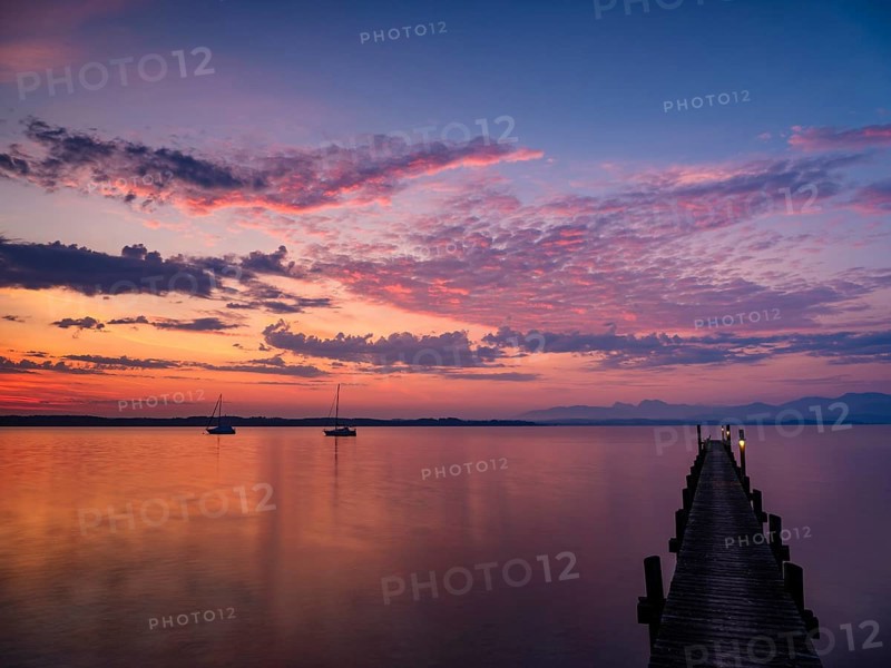 Illuminated clouds over sailing boats and jetty at Chiemsee at dawn, behind the Chiemgau Alps, Chiemgau, Upper Bavaria, Bavaria, Germany, Europe
