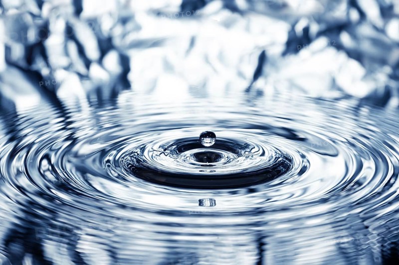 A drop of water falls onto the water surface and creates concentric circles, waves, rings