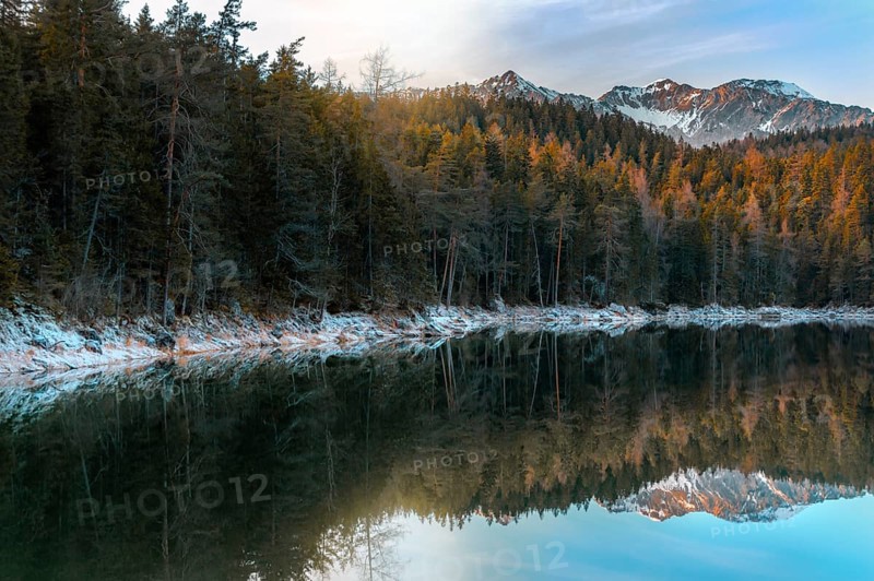Winter landscape with fir forest and the peaks of Alps mountains reflected in the Eibsee lake, on a sunny day, near Garmisch-Partenkirchen, Germany, Europe