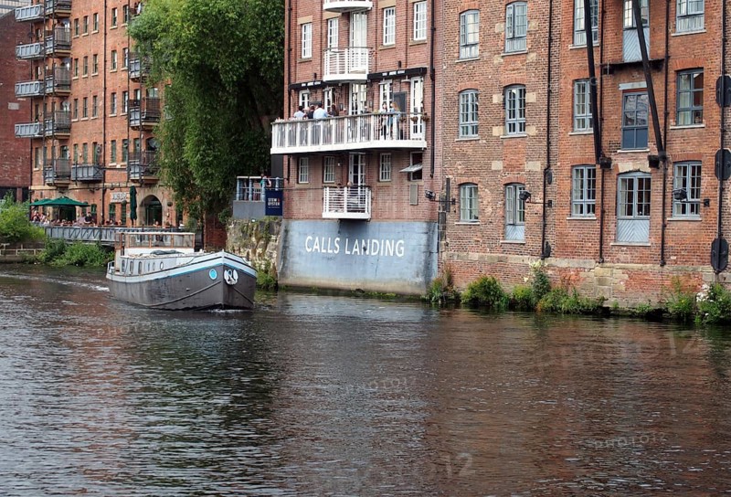 Leeds, west yorkshire, united kingdom: 16 july 2019: a boat sailing past calls laning in the river aire in leeds west yorkshire