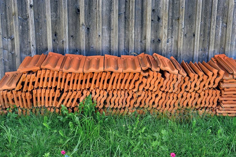 Stacked roof tiles in front of a wooden wall, Germany, Europe