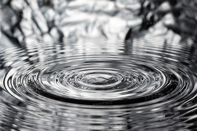 A drop of water causes concentric waves, circles and rings on the surface of the water