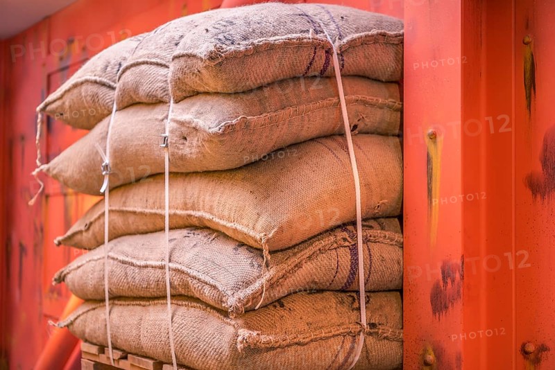 Cropped image with a pile of burlap bags full of goods, stacked on a pallet in a storage and ready for shipment