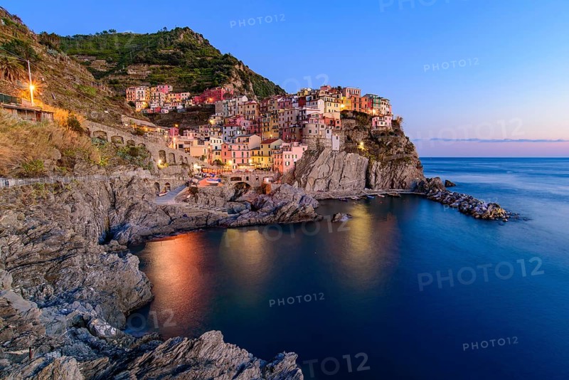 Sunset and night view of Manarola, one of the five Mediterranean villages in Cinque Terre, Italy, famous for its colorful houses and harbor, Europe