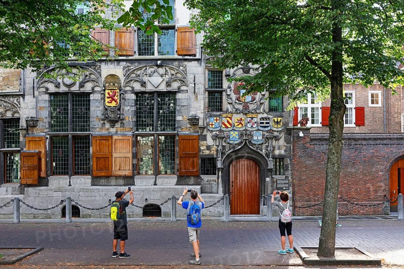 Historic city centre of Delft, tourists photograph Gemeenlandshuis van Delfland, town hall, oldest stone-built house in Delft, in Gothic architectural style, magnificent portal with coat of arms, Delft, South Holland, Netherlands